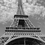 Monochrome photograph of the Eiffel Tower viewed from below on a cloudy day.
