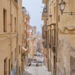 empty street in between concrete buildings during daytime